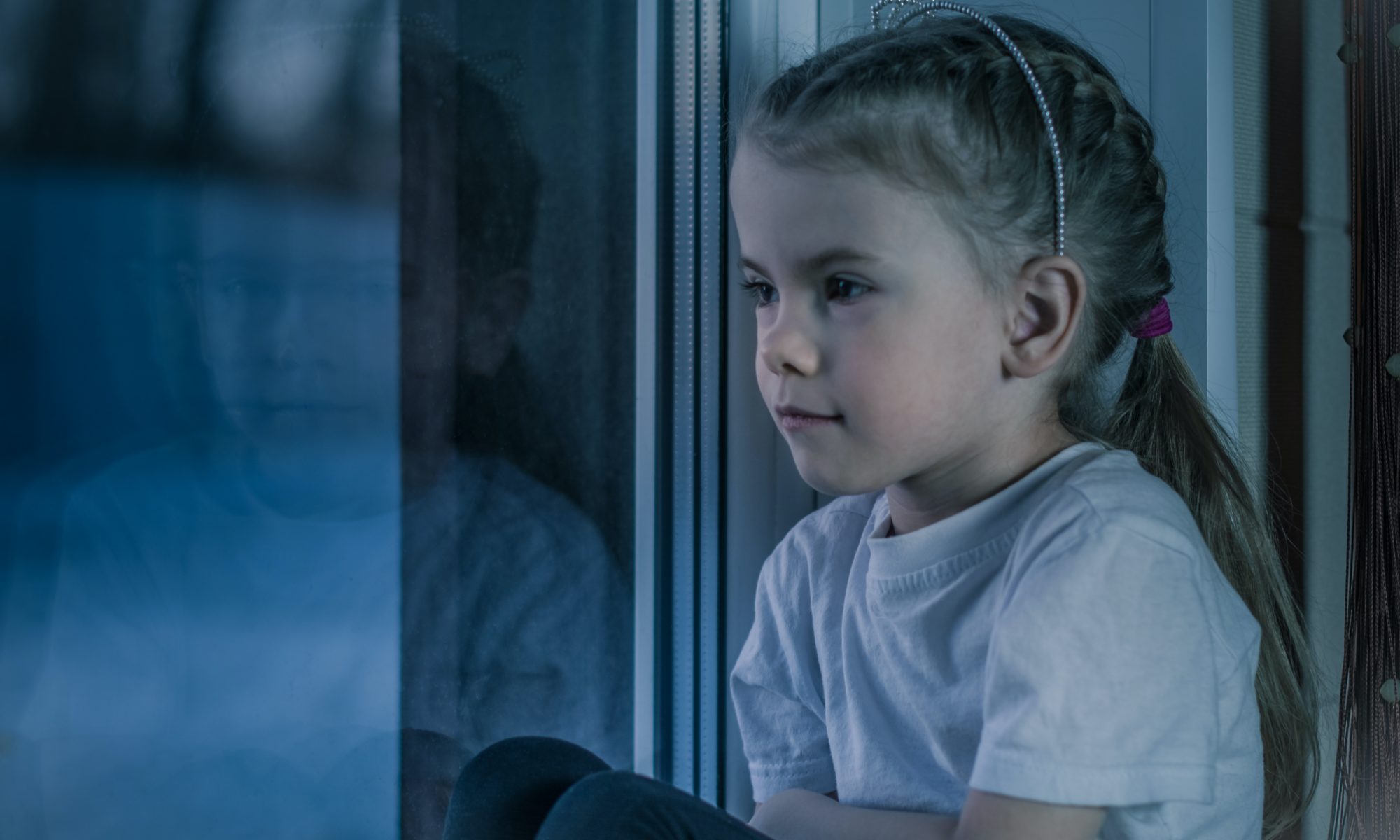 Sad young girl staring out of a window