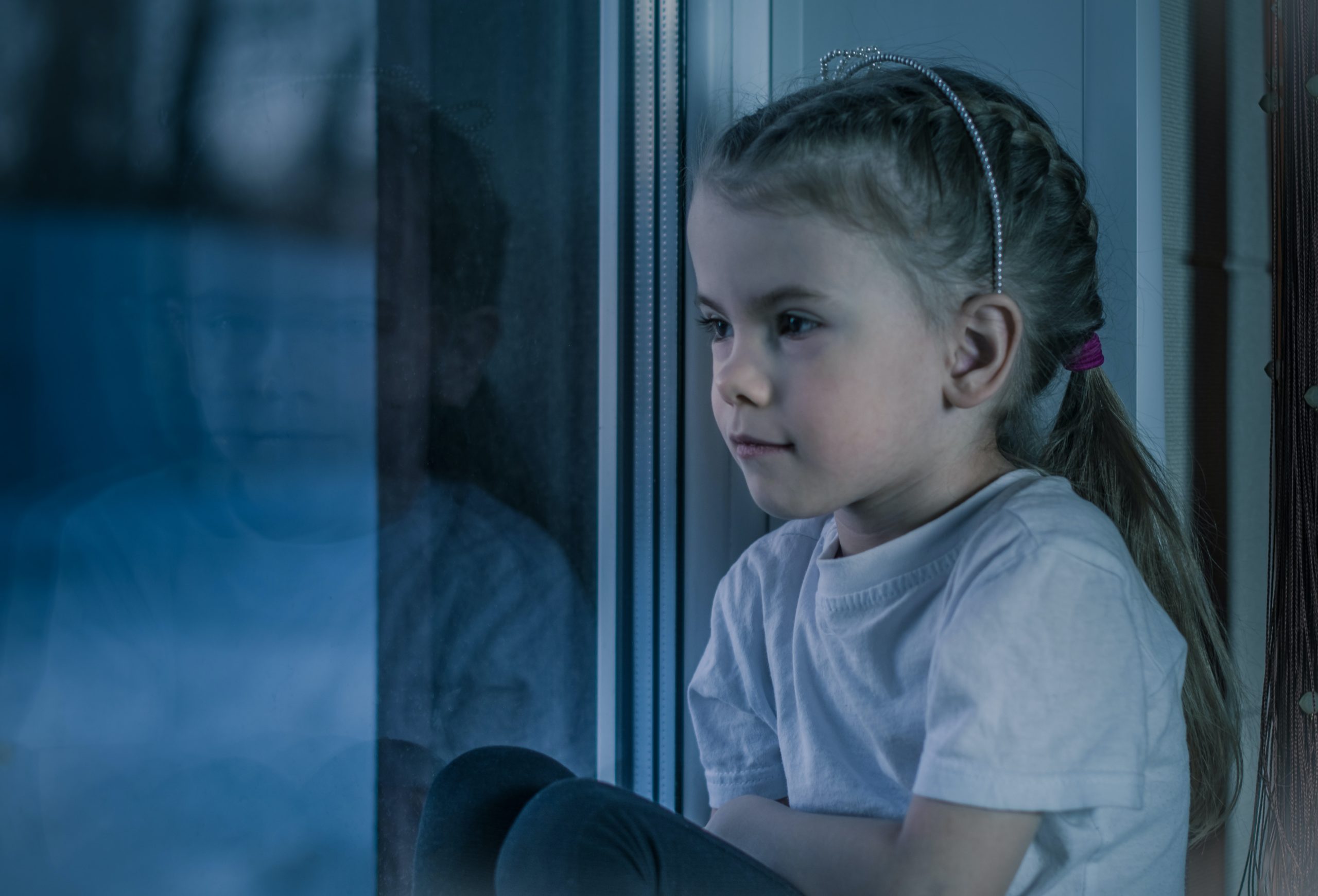 Sad young girl staring out of a window
