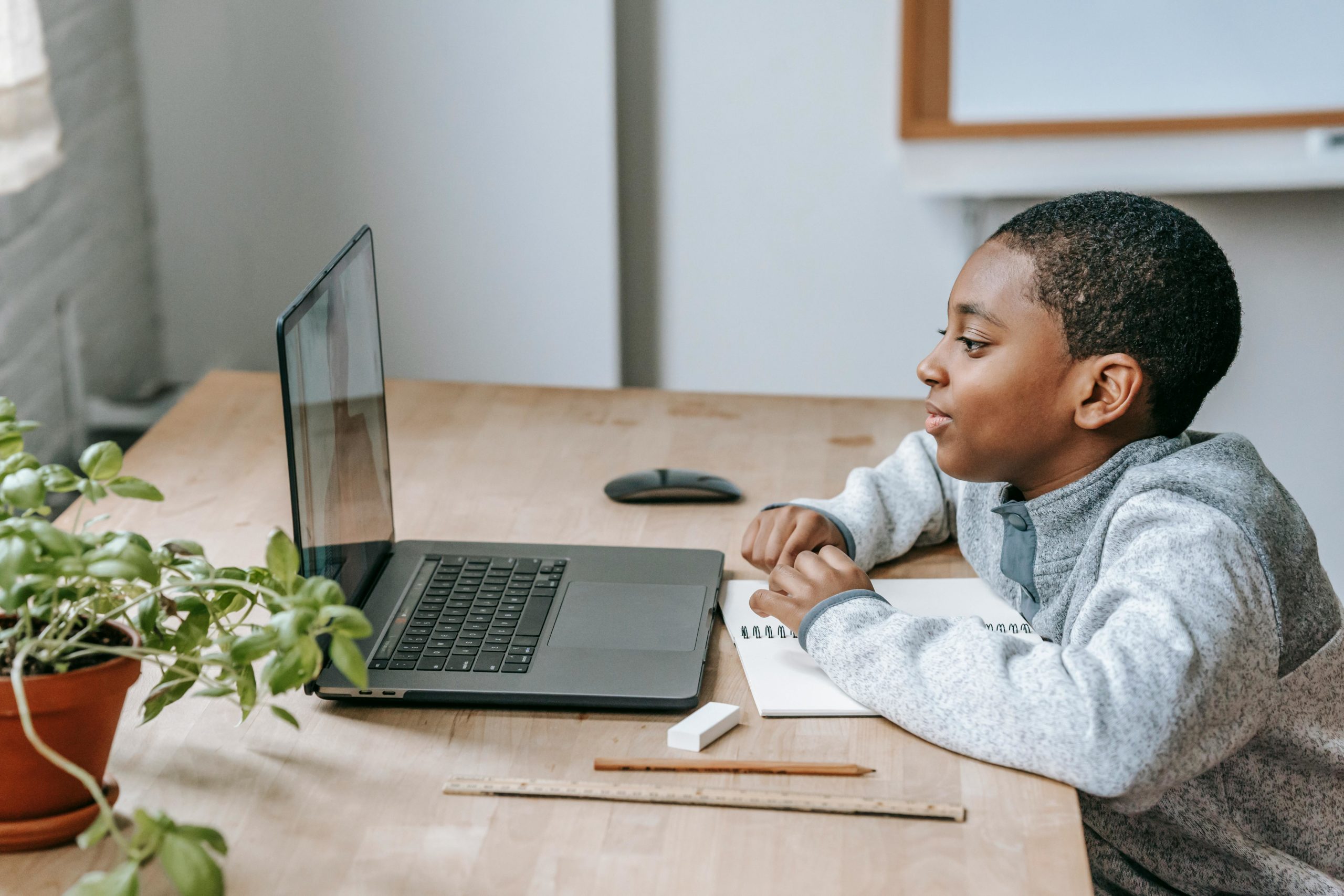 Un parent et son enfant collaborent sur un projet scolaire à la maison, illustrant l'implication parentale dans l'éducation malgré un planning de garde 70/30.