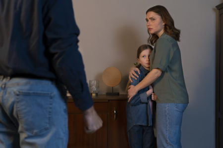 A mother protectively hugging her daughter during a tense moment with the co-parent, illustrating the emotional impact of high-conflict co-parenting and the importance of child safety in separated families.