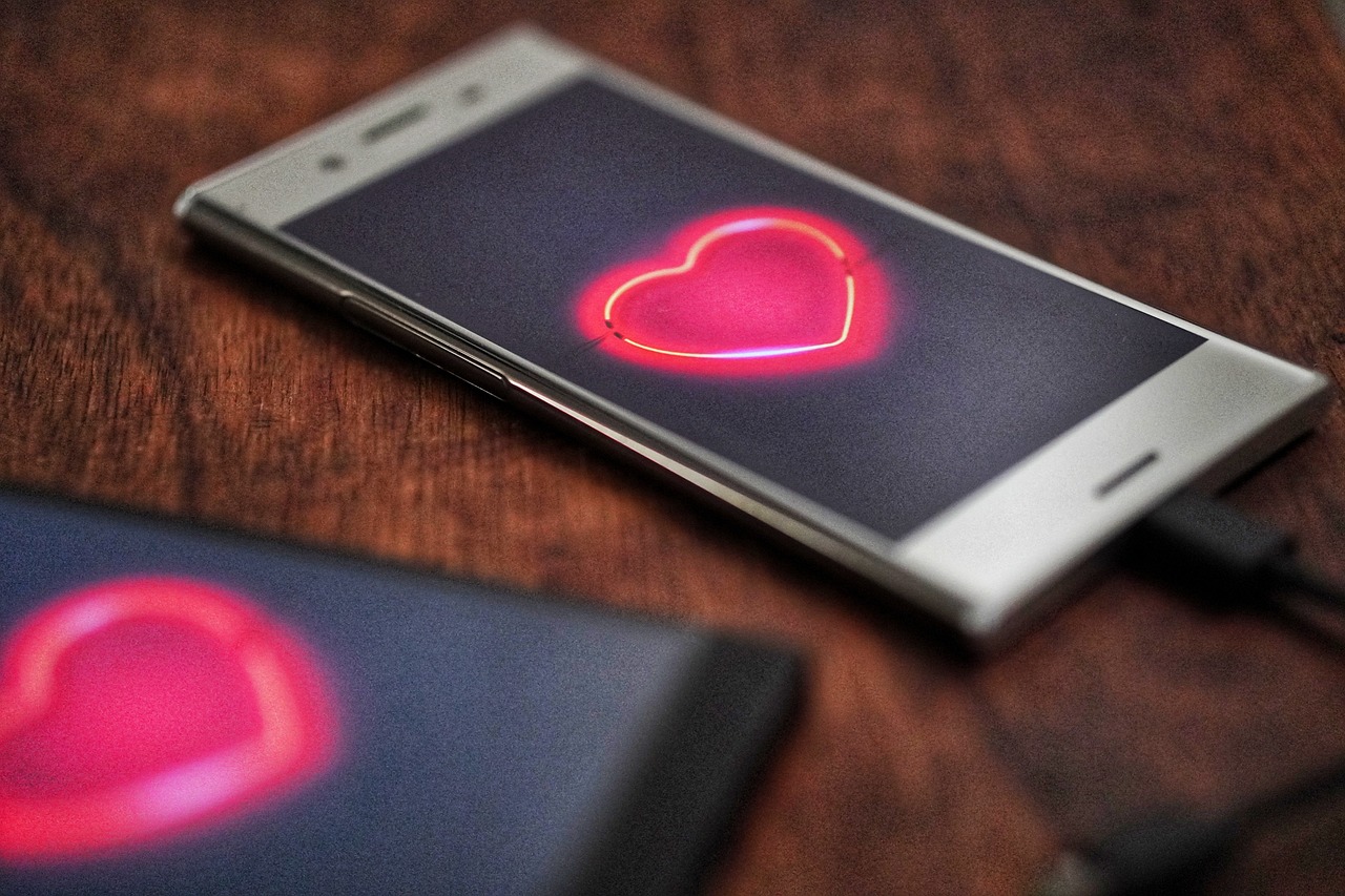 A smartphone displaying a glowing heart symbol, illustrating the emotional complexity and new connections that might arise during the divorce process. While the temptation to seek companionship may seem appealing, dating during a divorce can complicate legal matters, emotional recovery, and family dynamics. It’s crucial to take time for healing and reflect before entering a new relationship.